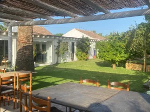Pergola terrace with dining tables looking onto the lawn and house at Villa Almar in Tarifa