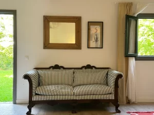 Antique striped sofa beside a window onto the garden at Villa Almar in Tarifa