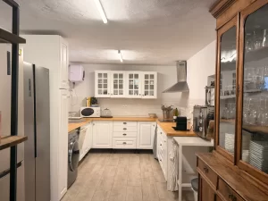 White fully equipped kitchen with wooden worktops and a glass cabinet at Villa Almar in Tarifa
