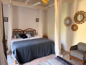 Double bed with white canopy curtains and rattan mirrors at Villa Almar in Tarifa