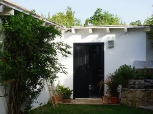 Whitewashed courtyard with a black door and potted plants at Villa Almar in Tarifa