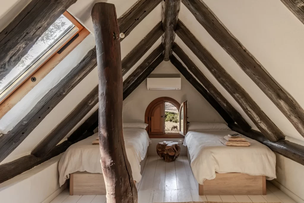 Attic twin bedroom at Villa Gran Paraiso with exposed beams and countryside view