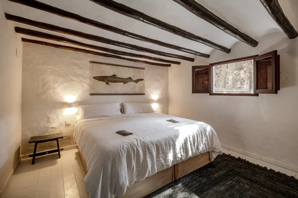 Rustic bedroom at Villa Gran Paraiso with beamed ceiling and fish artwork above the bed