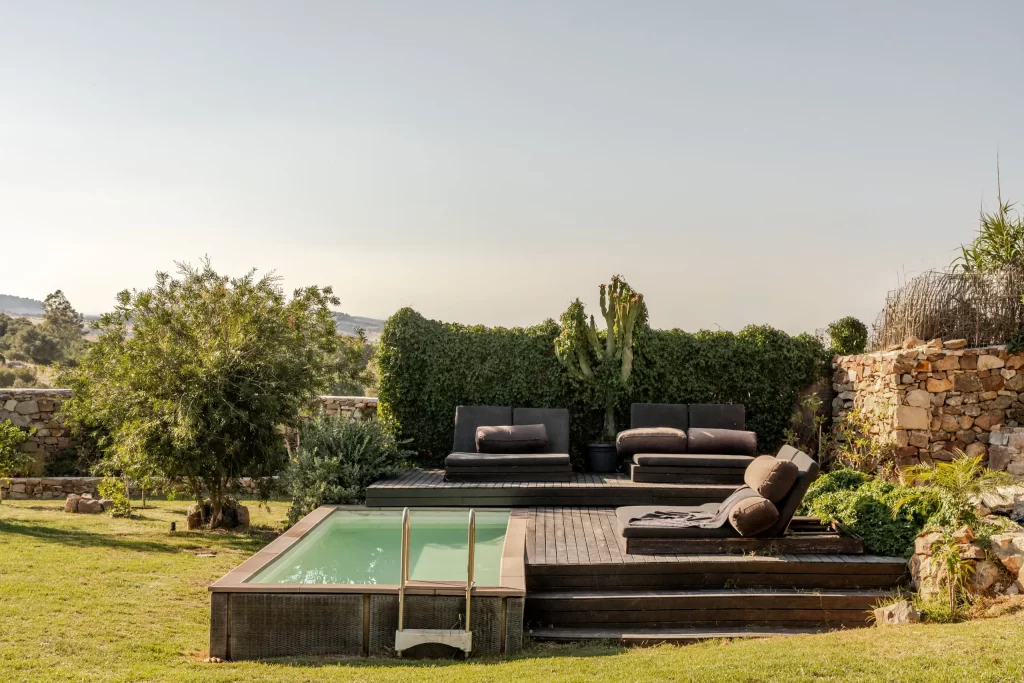 Elevated wooden pool deck at Villa Gran Paraiso with lounge sofas and stone walls