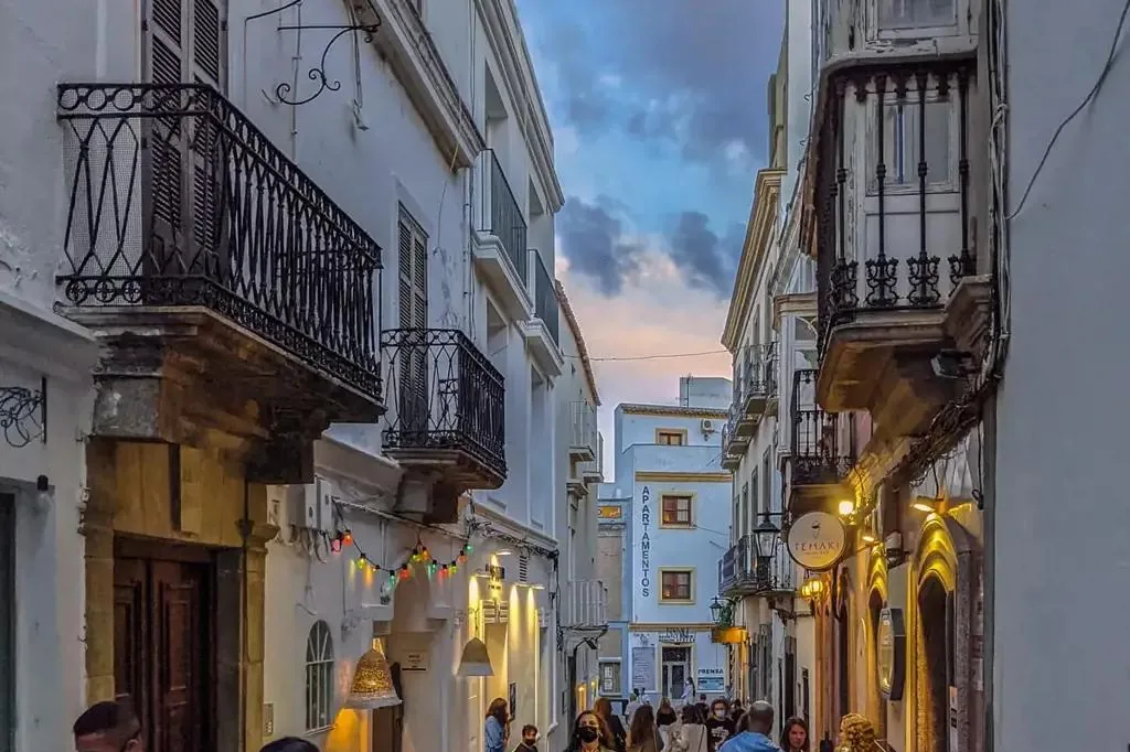 Whitewashed street in Tarifa old town at dusk, with balconies and lights