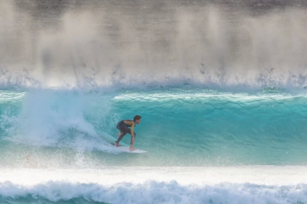 Surfer riding a turquoise wave on the coast near Tarifa