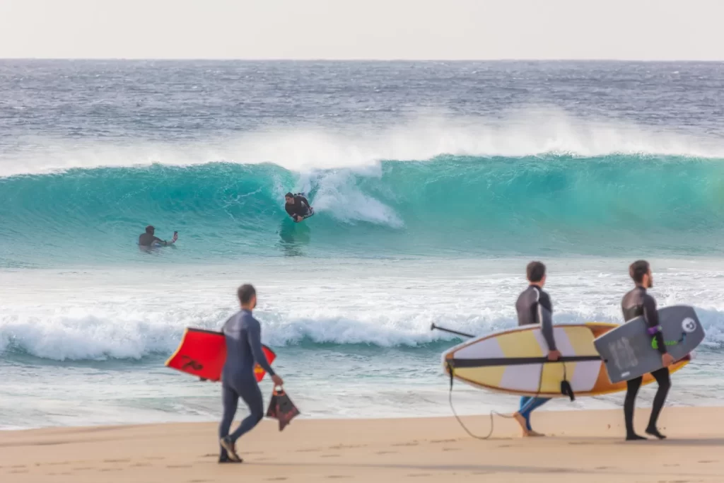 Surfers walking into the waves on a beach near Tarifa